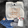 Flat lay of a sweatshirt with 'All booked for fall' text and graphics, jeans, socks, and ghost decoration on a textured surface by Fiction & Fibre.
