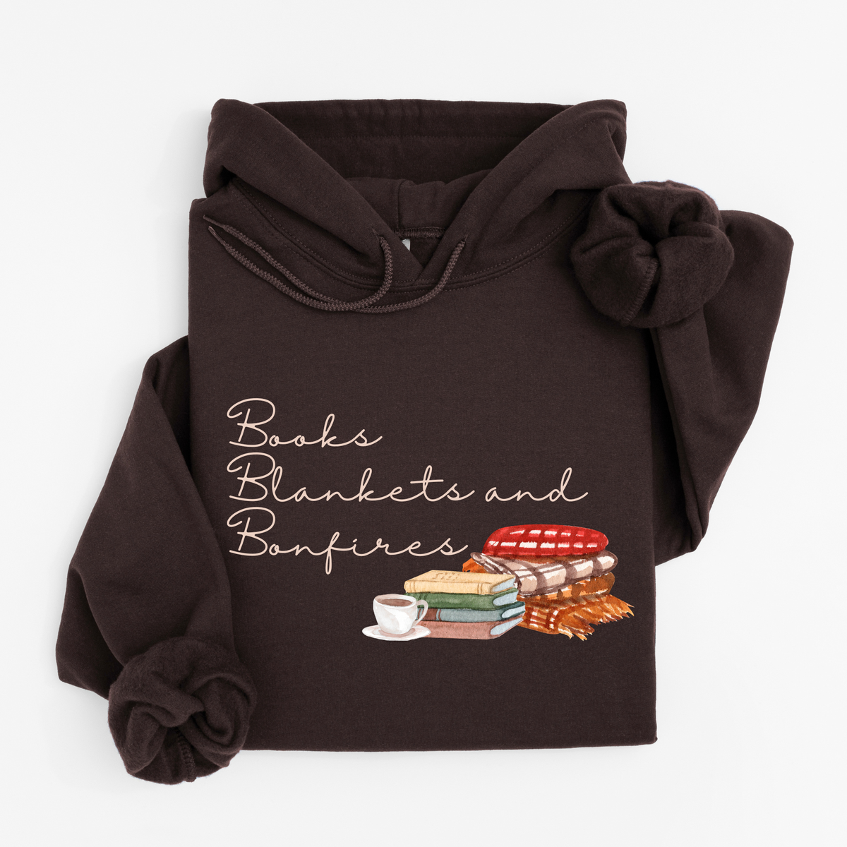 A dark brown hoodie laid flat on a light gray background, featuring a graphic print that reads 'Books Blankets and Bonfires' above an illustration of stacked books, a cup of tea, and cozy blankets.