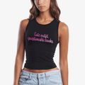 A woman wearing a black sleeveless crop tank top with pink script text reading 'Cute outfit, questionable books.' paired with light blue jeans, against a plain light gray background.