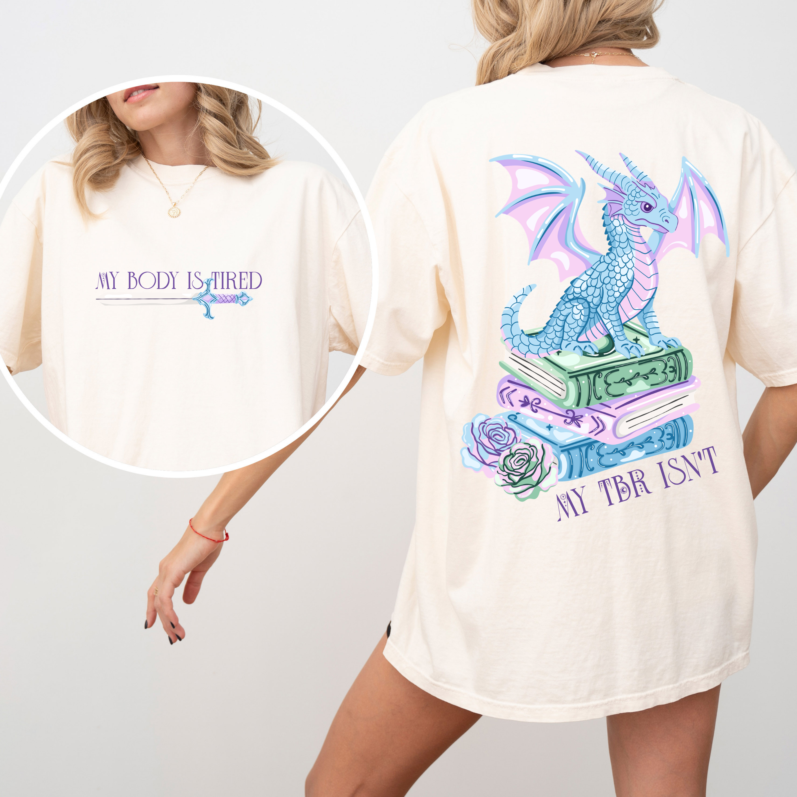 A woman wearing a ivory shirt that shows the front and the back. the front reads "my body is tired" and has a sword underneath. the back has a dragon sitting on books and reads "My tbr isnt"