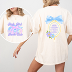 A woman wearing an ivory shirt showing the front and back. the front reads "sick girl book club" and has a stack of books wrapped in a bow. the back has a frame topped with a bow and reads "darling keep blooming you are doing beautifully"