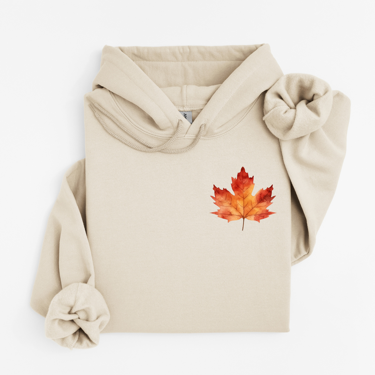A beige pullover hoodie with a watercolor-style red and orange maple leaf graphic on the left chest, styled flat on a white background.